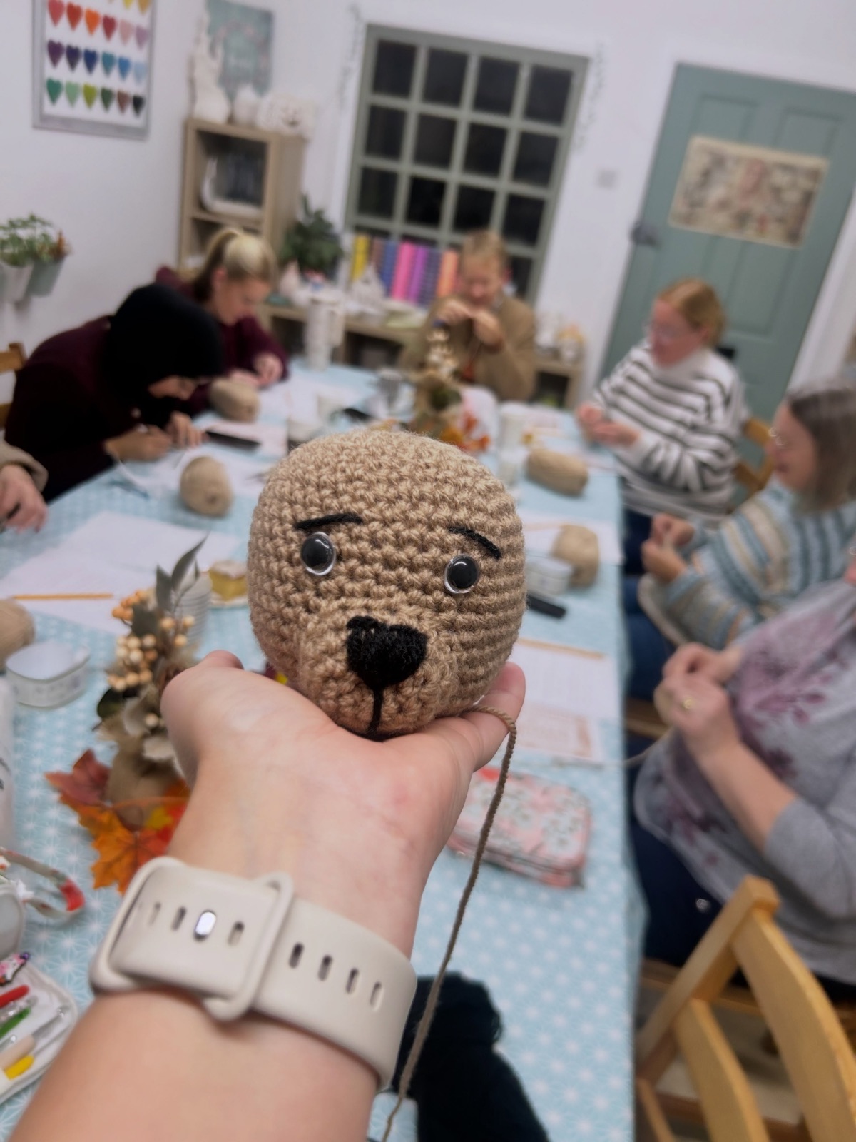A half-finished crocheted teddy bear held up at one of Rachael's workshops